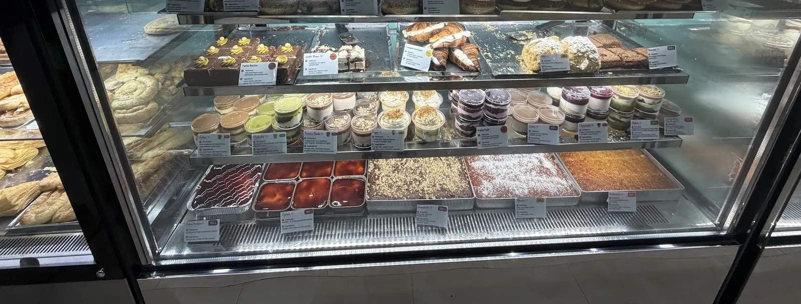 The pastry counter: cakes, cups, trays and cookies on four glass shelves