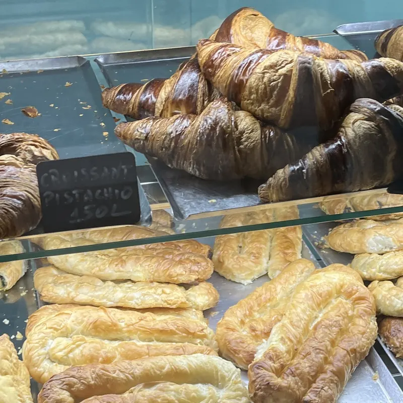 Croissants piled on a tray behind a chalk tag